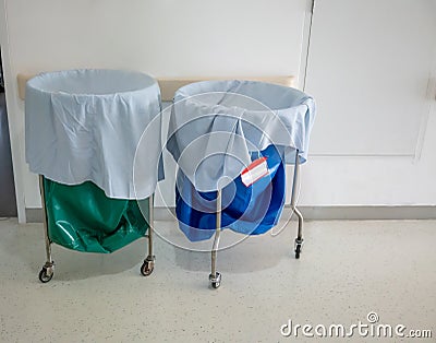 A pile of used clothes and infectious substances in hospital movable trolley with green bag and blue bag. Stock Photo