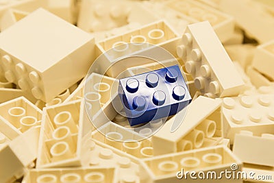 Pile of white color building blocks with selective focus and highlight on one particular blue block using available light Stock Photo