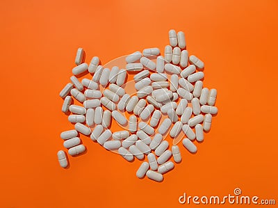Pile of white pills on orange background. The upper angle of view. The concept of dietary supplements Stock Photo