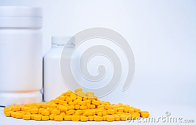 Pile of yellow tablets pills near plastic pills bottle with blank label on white background with copy space. Ibuprofen Stock Photo
