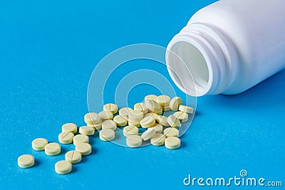 A pile of yellow tablets from a white plastic jar Stock Photo