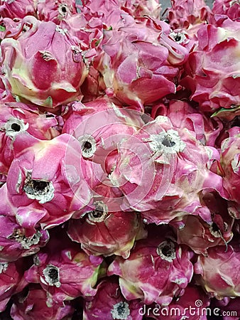 Piles of fresh dragon fruit in the market, the dominant color is red and slightly green. Fruits rich in vitamins. Stock Photo