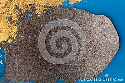 Piles of gold sequins on blue smudges of paint. Golden copyspace. Stock Photo