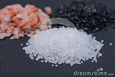 Piles of Hawaiian Black Lava Sea Salt, Coarse White Sea Salt and Himalayan Pink Salt on dark Stock Photo