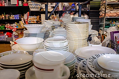 Piles of plates, crockery and ceramics on shelves in charity shop Stock Photo