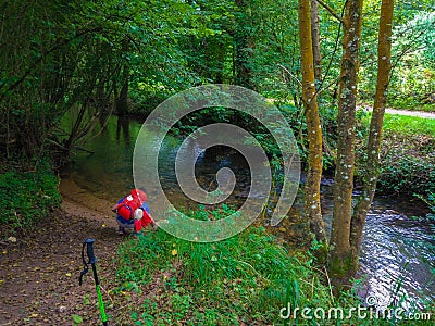 Pilgrim or backpacker drinking water from a river in middle of t Stock Photo