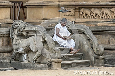 A pilgrim to the Kelaniya Raja Maha Vihara near Colombo in Sri Lanka sits on the steps to the shrine room. Editorial Stock Photo