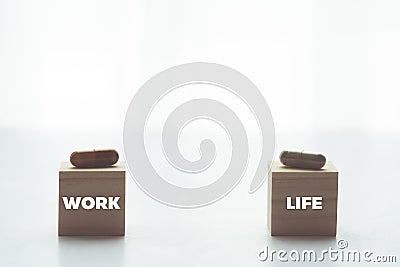 Pill or drug capsule that stamp the word work or life is placed on the wooden cube. The decision to choose between work or life. Stock Photo