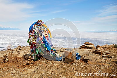 A pillar with multicolored ribbons for making wishes, offerings for spirits on a stone. Stock Photo
