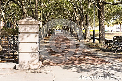 Pillar and tree-lined, shaded brick walkway in Charleston Riverfront Park Stock Photo