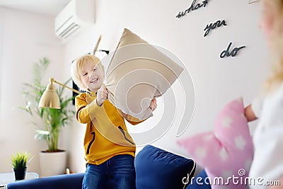 Pillow fight. Mischievous preschooler children jumping on a sofa and hitting each other with pillows.Active games for siblings at Stock Photo