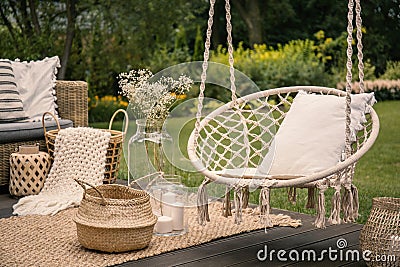 Pillow on hanging chair and basket on carpet in the garden during spring Stock Photo