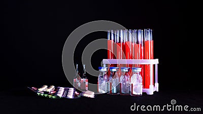 Pills on a background of test tubes with red liquid and ampoules on a black background Stock Photo