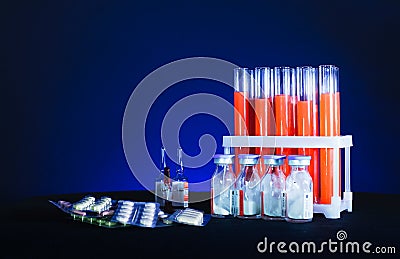 Pills on a background of test tubes with red liquid and ampoules on a black background Stock Photo