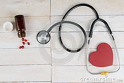Pills in botle with stethoscope and heart on white wooden table. Medical concept. Top views with clear space Stock Photo