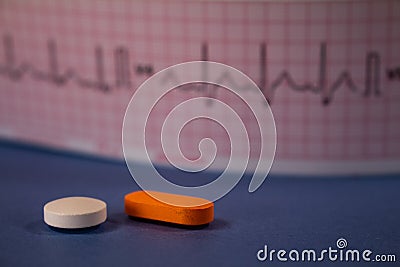 Pills of colors in a neutral background. Electrocardiogram strip out of focus Stock Photo