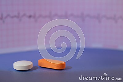 Pills of colors in a neutral background. Electrocardiogram strip out of focus Stock Photo