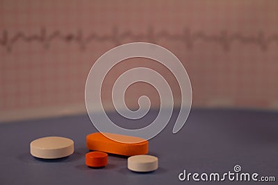 Pills of colors in a neutral background. Electrocardiogram strip out of focus Stock Photo