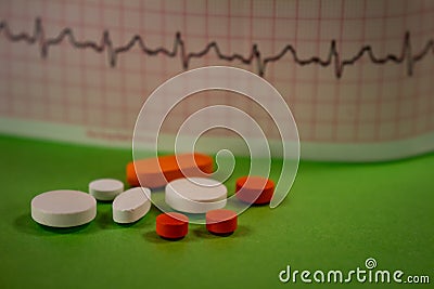 Pills of colors in a neutral background. Electrocardiogram strip out of focus Stock Photo