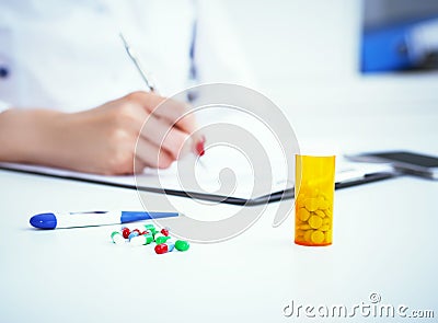 Pills and electronic thermometer laying on the table with female medicine doctor working on background. Medicine doctor Stock Photo