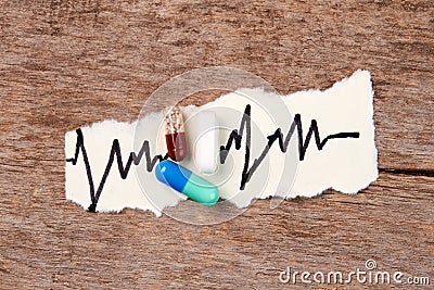 Pills, heartbeat image, wooden table. Stock Photo