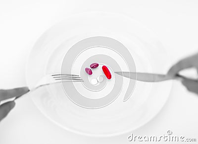 Pills on a plate with fork and knife. Diet concept. Stock Photo