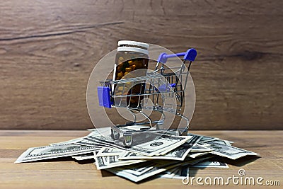 Pills in a shopping basket on a heap of American dollars. Economy concept of spending money on medicines and pills. Medical pill Stock Photo