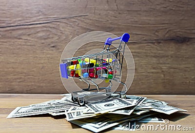 Pills in a shopping basket on a heap of American dollars. Economy concept of spending money on medicines and pills. Medical pill Stock Photo