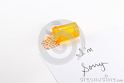 Pills spilling out of medicine bottle with I'm Sorry note, implication suicide overdose Stock Photo