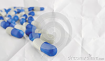 Pills spilling out of pill bottle on crumpled paper Stock Photo