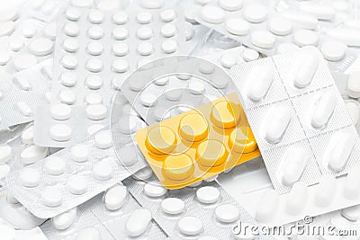 Pills in yellow package over white tablets Stock Photo