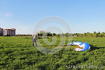 pilot newcomer paraglider is trained on the ground to lift up and hold the blue-white paraplane. Editorial Stock Photo