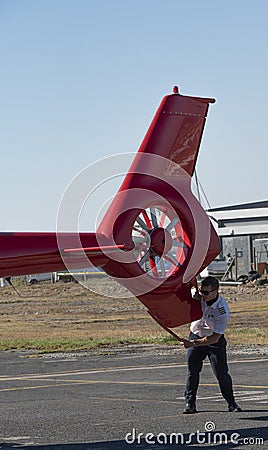 Pilot supporting a helicopter tail rotor as it is being pushed into a hangar. Editorial Stock Photo