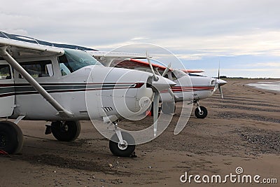 Light planes sitting on the wet packed sand bar Stock Photo