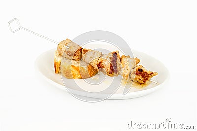 Skewer of meat on a slice of bread and on top of a white plate. Stock Photo