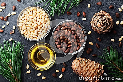 Pine nuts, oil and cedar cones on black table top view. Organic and healthy superfood. Stock Photo