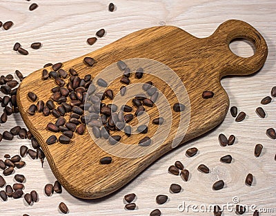 Pine nuts scattered on the table and on a wooden cutting Board. Stock Photo
