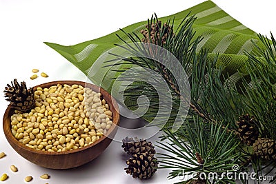 Pine nuts in wooden bowl, cedar branch and cones Stock Photo