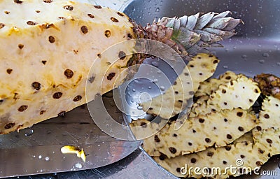 Pineapple being peeled over a stainless steel sink Stock Photo