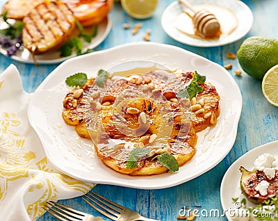 Pineapple dessert, Grilled slices of pineapple with the addition of honey, roasted pine nuts, fresh lemon balm and Stock Photo