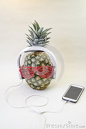 Pineapple with disco party glasses, white headphones and smartphone Stock Photo