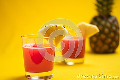 Pineapple juice in glass closeup near sliced fruit with spash and dripping liqid for summer vibes Stock Photo