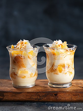 Pineapple, peach, Coconut Trifle dessert mouse in a glass on a dark background with copy space. Vegan recipe dessert concept. Stock Photo