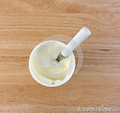 Pineapple yogurt in container with spoon on table Stock Photo