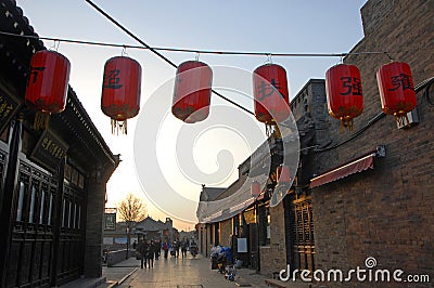 Pingyao in Shanxi Province China: Street scene in Pingyao ancient city at sunset with red lanterns Editorial Stock Photo