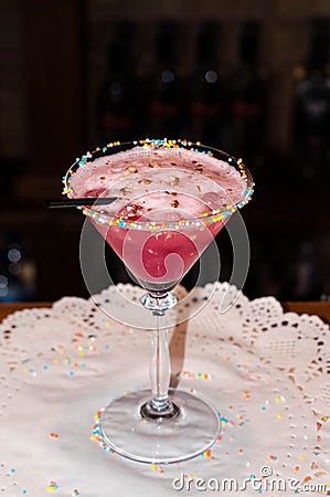 pink alcohol cocktail in glass with high leg with black straw on white napkin in restaurant Stock Photo
