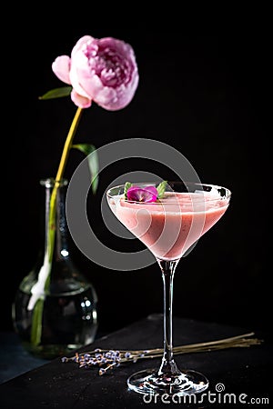 Pink alcoholic cocktail decorated with roses and mint close-up on black background with copy space Stock Photo