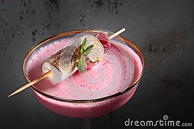 Pink alcoholic cocktail in a wine glass. The cocktail is decorated with marshmallows. Close-up. Stock Photo