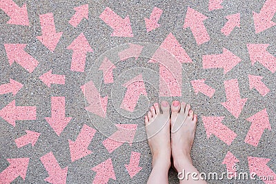 Pink Arrow Choice Concept. Female Bare Feet with Pink Nail Polish Manicure Standing and Many Direction Arrows Choices on the Road Stock Photo