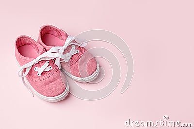 Pink baby shoes on pink background, concept of first steps, birthday, expectation, pregnancy, maternity, motherhood, parenthood. Stock Photo